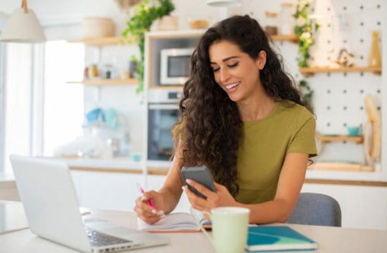 women with laptop looking at phone