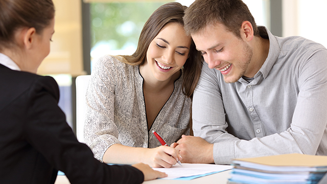 Young couple signing a documents together at office