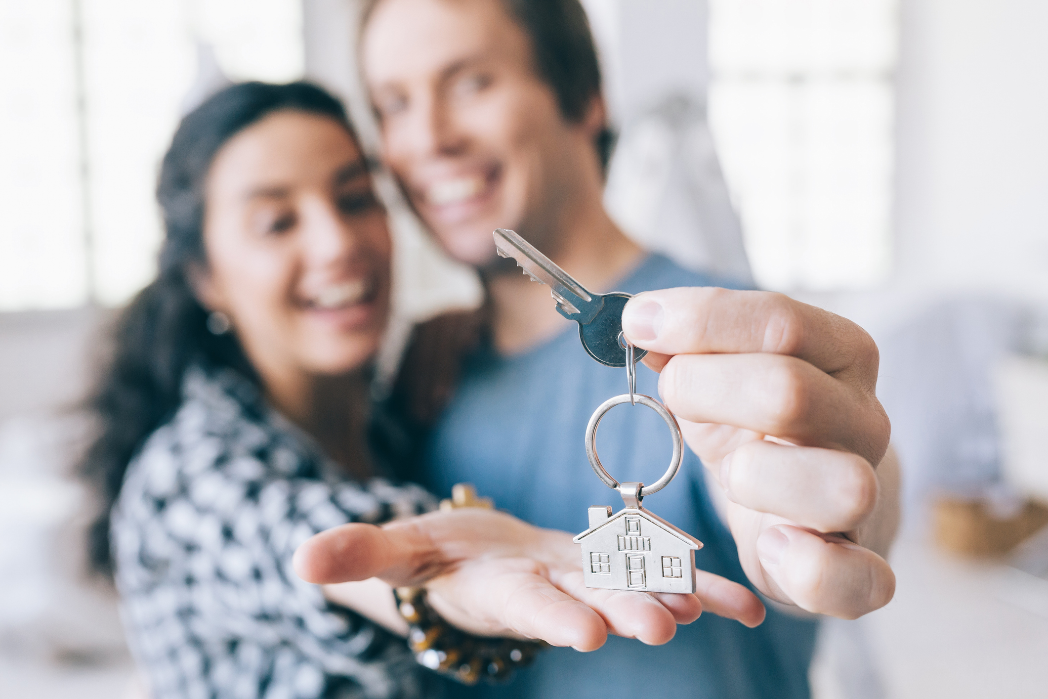 Couple cheerful home owners holding a key to their new home